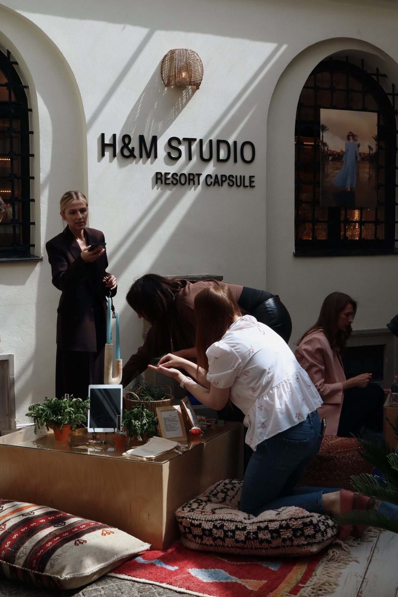 Goście przy niskim stoliku ekspozycyjnym pod ścianą H&M Studio Resort Capsule na Patio